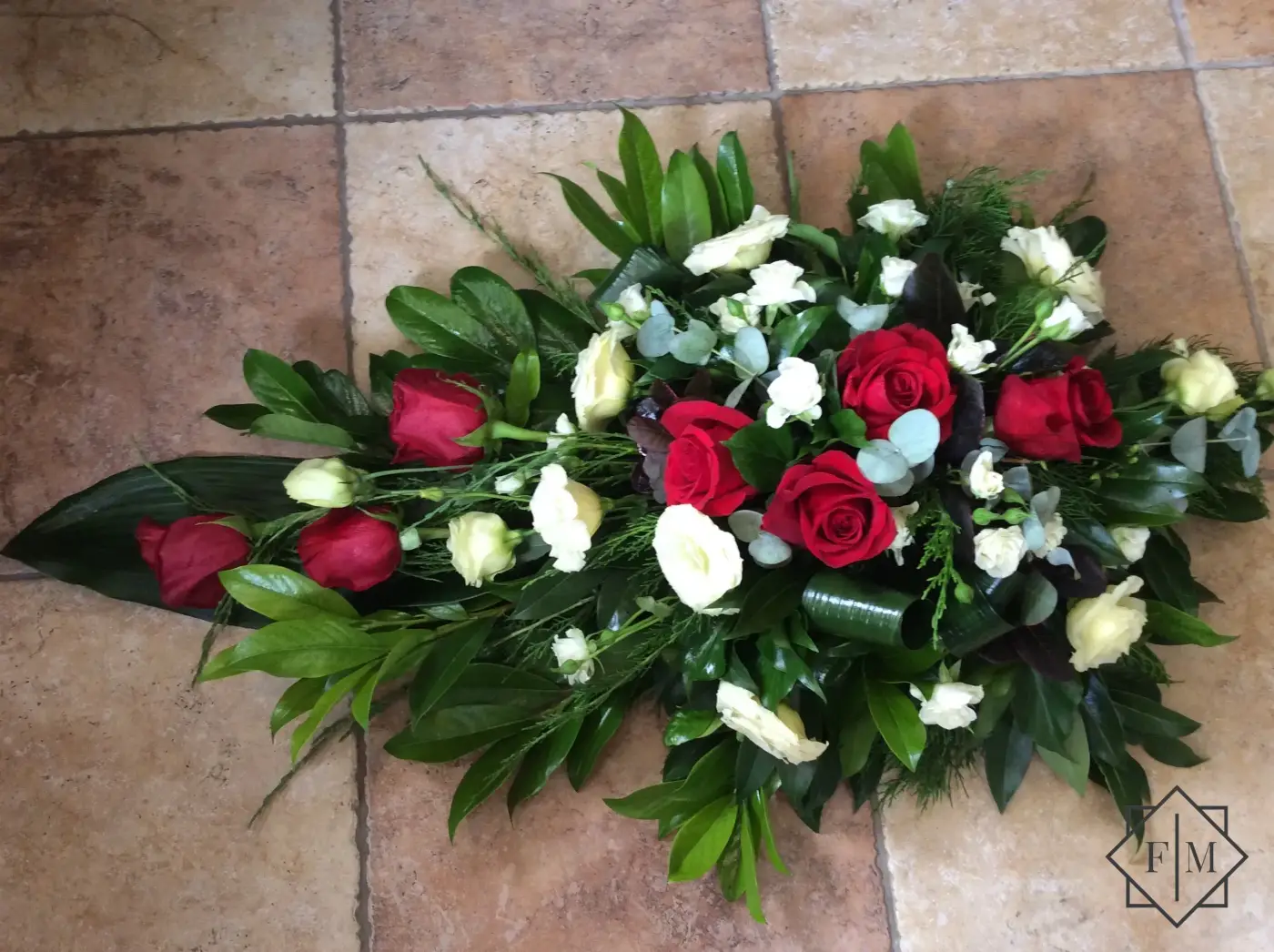 Klasszikus kialakítású sírcsokor vörös és fehér színű virágokkal, örök zöldekkel és vízutánpótlással növényeknek. A búcsú személyesebbé tehető, ha kegyeleti csokorba kéred elhunyt kedvenc virágait.