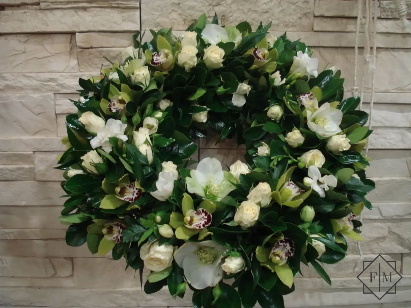 Nagyobb méretű, klasszikus görög koszorú zöld, fehér színvilágban. Méltó választás búcsúzásra kedves, visszafogott emberrel; Segítünk Neked, hogy a búcsú a lehető legszebb és legszemélyesebb legyen. Mond el nekünk, milyen ember volt az elhunyt, mit szeretett, hogyan élt. Mi gondoskodunk róla, hogy ez kifejeződjék a virágkompozíciókban