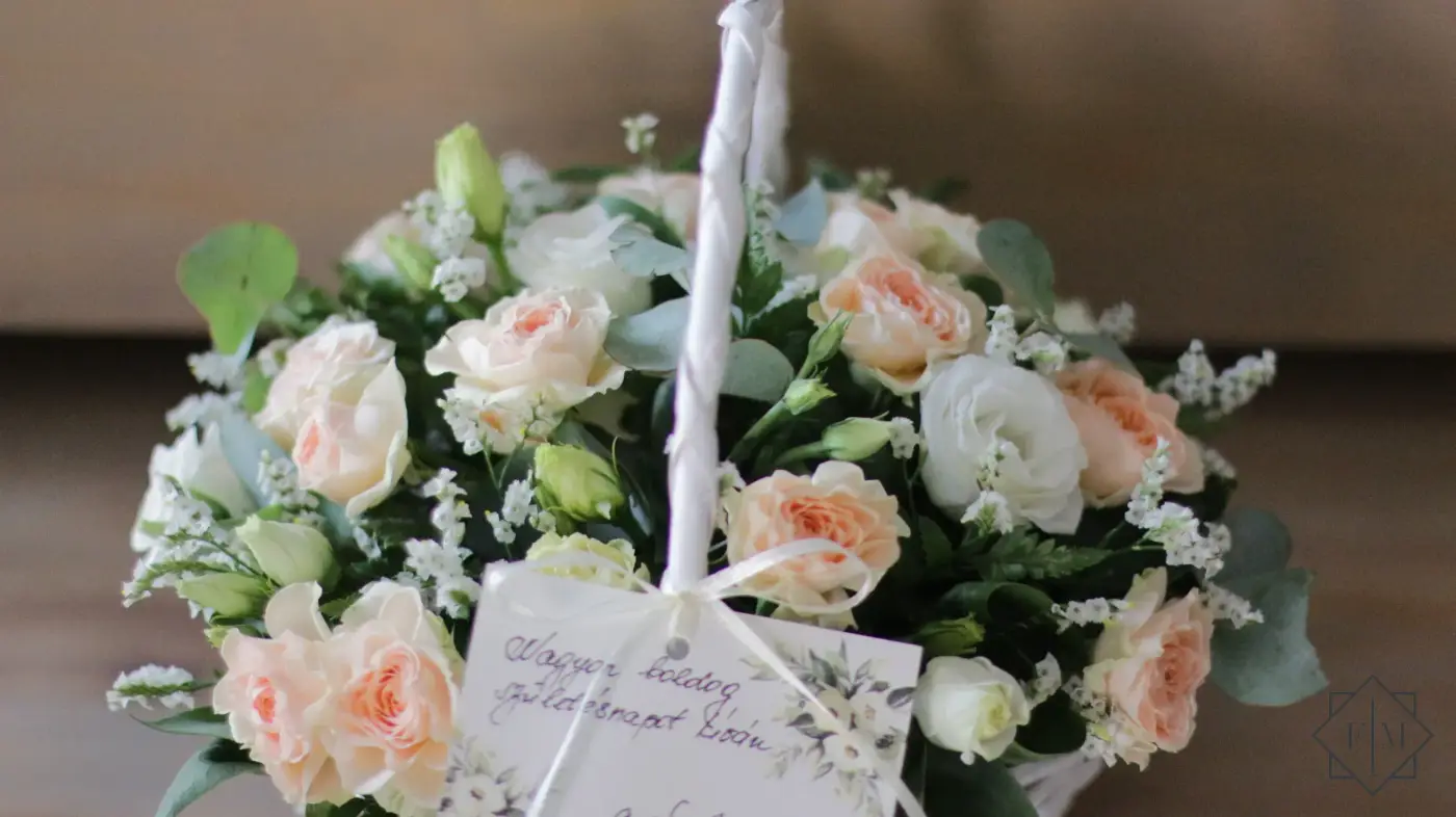 Bájos, kicsi méretű, kosár fehér lisianthussal, púder-barack színű csokros rózsákkal és finom kiegészítőkkel. Az alkalom maradandó élményéhez van lehetőséged összeállítani meglepetést ajándékozott kedvenc virágaiból. Sikered garantált, hiszen ehhez mi is adjuk 100% garanciát.